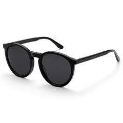 Arch Bio-Acetate Blackサングラスを斜め前方から捉えた画像です。ブラックのラウンドフレームが描く柔らかな曲線と、テンプルに刻印されたゴールドのDaniel Wellingtonロゴが確認できます。