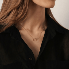 ブラックシャツの襟元に映えるElan Unity Necklaceの着用シーンです。ローズゴールドの細いチェーンが首元に優雅になじみ、2つのインターロッキングリングが鎖骨の下で控えめに輝きます。