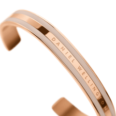 Emalie Bracelet Desert Sand Rose Goldのクローズアップ画像です。ローズゴールドの光沢あるスチールフレームにデザートサンドカラーのエナメルが施された二重構造と、中央に刻印されたDaniel Wellingtonのロゴがご覧いただけます。
