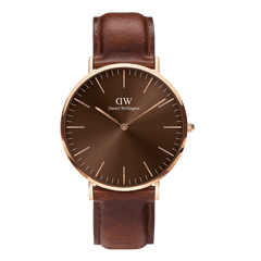Daniel Wellington Classic St Mawes Amberの正面画像です。アンバーブラウンのサンレイ仕上げ文字盤に、ローズゴールドのバーインデックスと針が映え、ダークブラウンのレザーストラップが温かみのあるトーンでまとめられています。