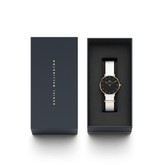 Petite Dover Black Rose Goldがダークネイビーのギフトボックスに収められた様子です。ブラックの文字盤とホワイトのNATOストラップをあしらった腕時計が、ボックスの蓋とともに上から撮影されており、贈り物にぴったりの上品なパッケージをご覧いただけます。