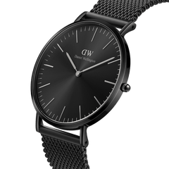 Classic Mesh Onyx Blackを斜めからとらえたクローズアップ画像です。サンレイ仕上げのブラック文字盤が光を受けて放射状の陰影を描き、薄型ケースの側面やリューズのディテールが際立ちます。