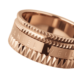 Elevation Ring Rose Goldのクローズアップ画像です。ピラミッド型のスタッズが精巧に施され、中央バンドにはDaniel Wellingtonのロゴが刻印されています。PVDローズゴールドメッキの上品な輝きが際立つデザインです。