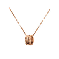 Elevation Necklaceのペンダントトップを斜め下から捉えたクローズアップ画像です。ローズゴールドの三層バンドに刻まれたDaniel Wellingtonのロゴとスタッズの凹凸が、光を受けて立体感のある陰影を描いています。