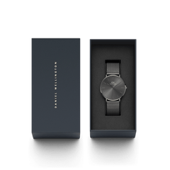 Daniel Wellington Classic Mesh Graphiteのパッケージ画像。ブランドロゴが箔押しされたネイビーカラーの化粧箱と、黒いクッショントレーに収められたグラファイトカラーの本体が並んでいます。ギフトにも最適な上品な仕様です。