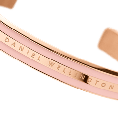 Emalie Bracelet Dusty Rose Rose Goldのロゴ刻印部分を正面から大きく捉えた接写画像です。ローズゴールドの中央バンドに刻まれたDaniel Wellingtonの文字と、両側のダスティローズエナメルの滑らかな質感が確認できます。