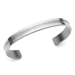 Elan Braceletシルバーを斜めから捉えた画像です。ポリッシュ仕上げのエッジとサテン仕上げの中心部分が光を反射し、異なる輝きを放ちます。Daniel Wellingtonのロゴが刻印されたオープンカフデザインが特徴です。