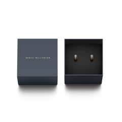 Daniel Wellingtonのロゴが箔押しされたネイビーの専用ギフトボックスに収められたEmalie Earrings Rose Gold Black。ブラックエナメルとローズゴールドのコントラストが美しい小ぶりなフープピアスが、ブラックのクッション上に丁寧にセットされています。