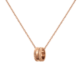 Daniel Wellington Elevation Necklaceのペンダントトップを正面から捉えた商品画像です。三層構造のバンドにスタッズパターンとブランドロゴが刻まれたローズゴールドのリング型ペンダントが、細身のケーブルチェーンに通されています。