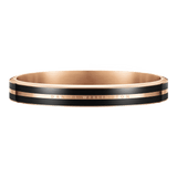 Daniel WellingtonのEmalie Infinite Rose Gold Blackバングルブレスレットを正面から捉えた画像です。ブラックエナメルの2本のラインが中央のローズゴールドバンドを挟み込み、同色で刻印されたブランドロゴが控えめにあしらわれたシームレスなデザインです。