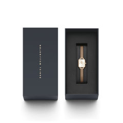 Daniel Wellingtonのギフトボックス入りQuadro Mini Melrose。ネイビーカラーのボックスにゴールドのブランドロゴが箔押しされ、黒いクッショニングの上にローズゴールドのメッシュストラップとスクエアケースが美しく収められています。贈り物にぴったりの上品なパッケージです。