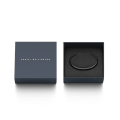 Daniel Wellington Classic Braceletのブラックが、ネイビーのブランド専用ギフトボックスに収められています。箱の蓋にはゴールドのブランドロゴがあしらわれ、ギフトにぴったりの上品なパッケージです。